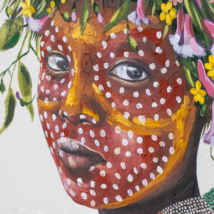 Peça de arte autoral com vestimenta amarela e colar azul em composição com arranjo de flores vibrantes.