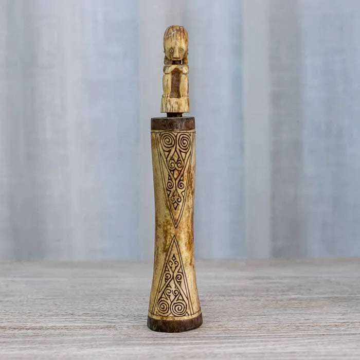 Grafismos geométricos e espirais tribais gravados na superfície da peça artesanal.