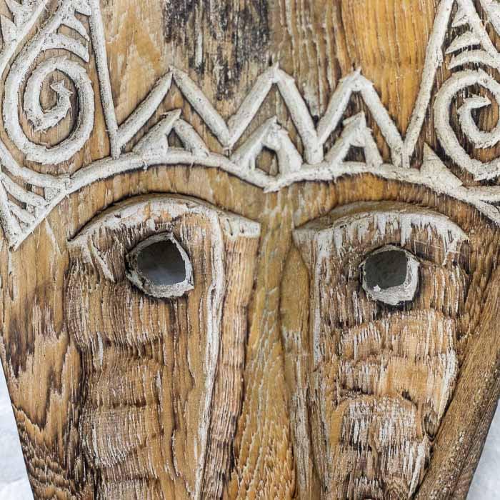 Máscara artesanal de 46cm de altura com textura de madeira bruta e design primitivo.