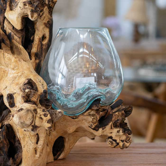 Detalhe do vaso de vidro soprado artesanal em tronco de madeira balinesa, revelando o processo natural de moldagem e o equilíbrio entre transparência e rusticidade. 