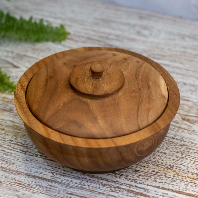 Peça de decoração étnica em madeira Teca utilizada como petisqueira para grãos em uma mesa de centro rústica.