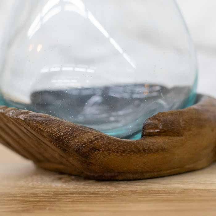 Escultura artesanal de mãos em oferta segurando vaso terrário em vidro soprado.