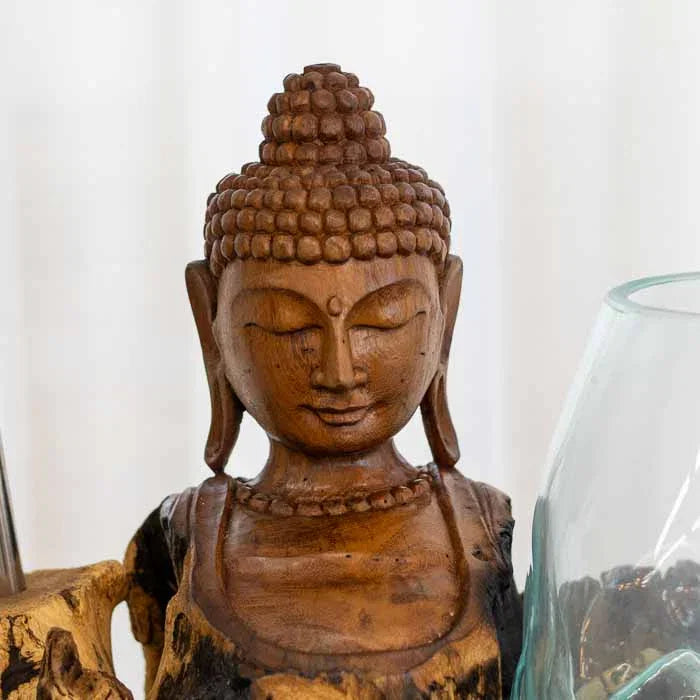 Detalhe do vidro soprado transparente "derretido" sobre escultura de Buda em tronco rústico. 