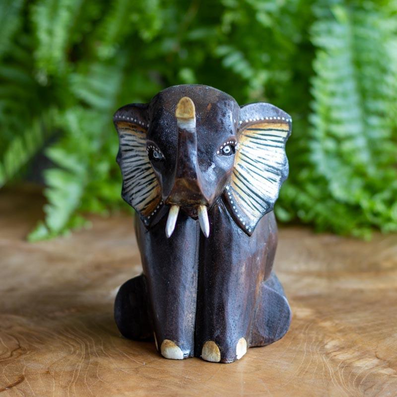 Peça decorativa em madeira artesanal representando elefante sentado.