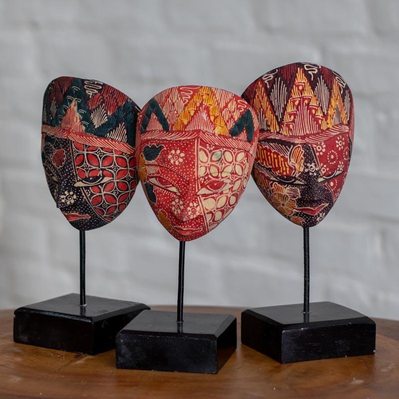 Escultura de mesa étnica de 23cm com máscara de madeira e haste metálica em ambiente de decoração sofisticada.