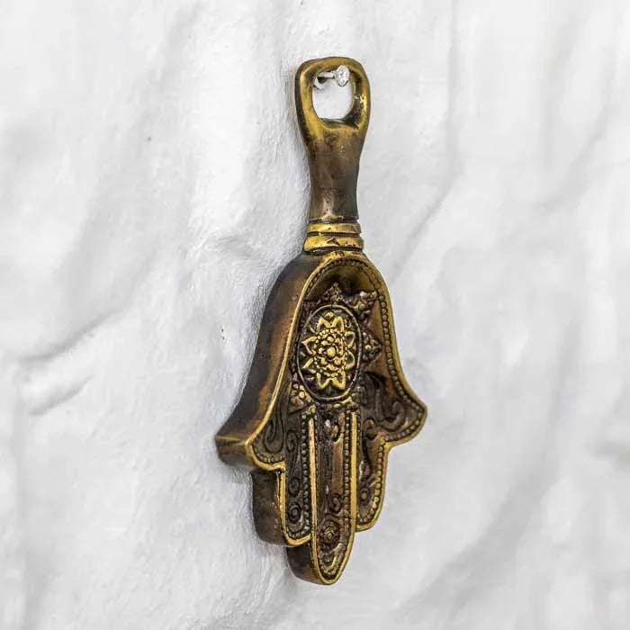 Utensílio de bar artesanal de Bali em liga metálica resistente posicionado contra parede branca rústica.