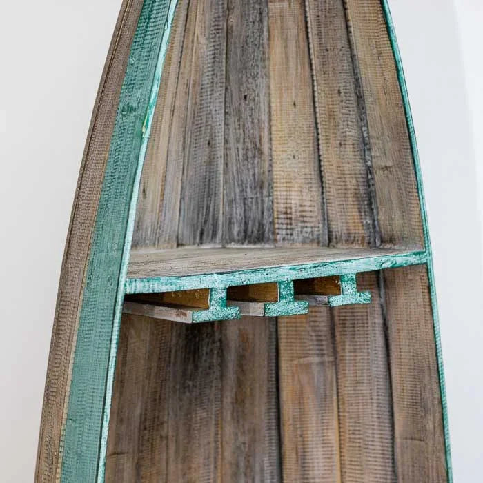 Móvel decorativo de Bali em formato de barco vertical, usado como adega de madeira artesanal com prateleiras internas e textura rústica. 