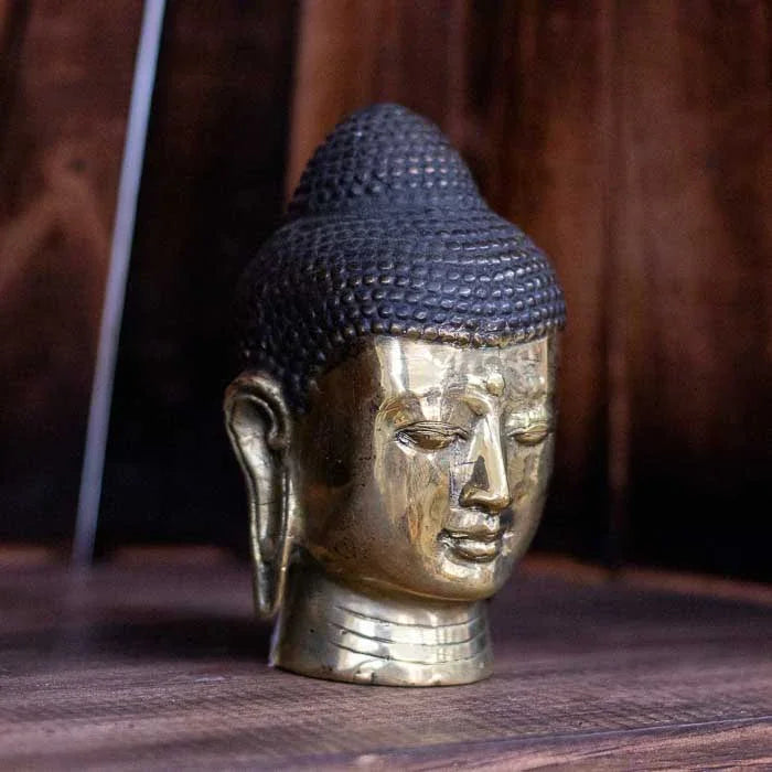 Cabeça de Buda dourada em bronze polido com expressão serena. 
