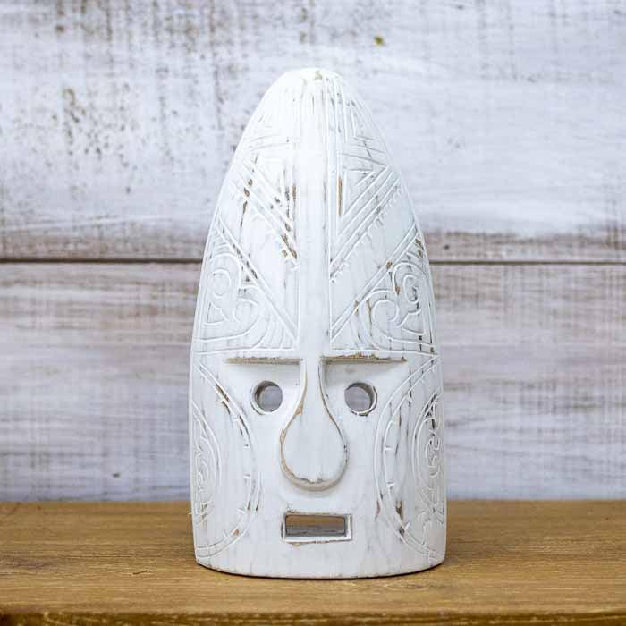Máscara decorativa em madeira clara com entalhes manuais simétricos em um design alongado e rústico.