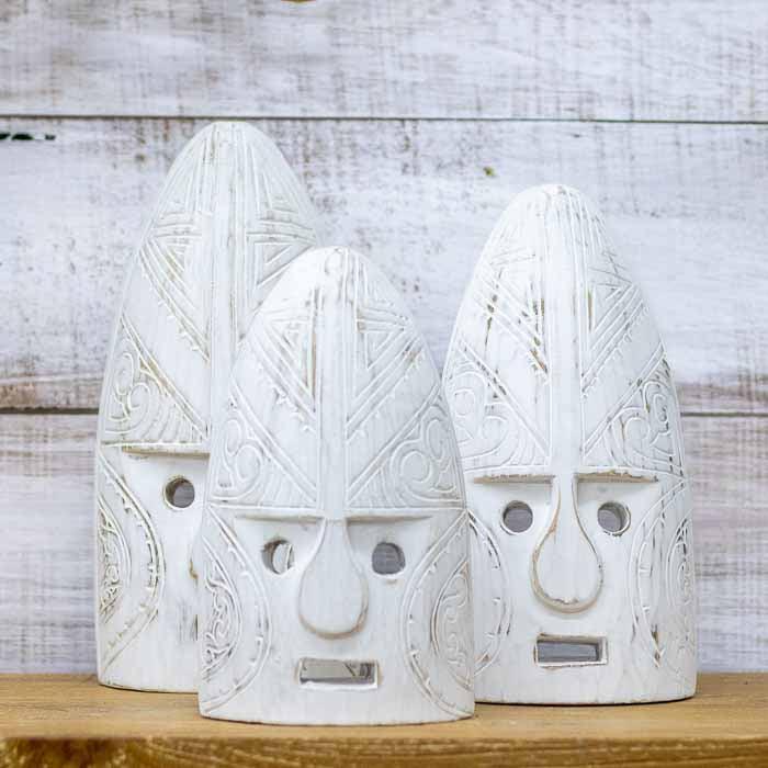 Máscara tribal de Timor em madeira maciça posicionada contra um fundo de madeira rústica, destacando o contraste de cores.