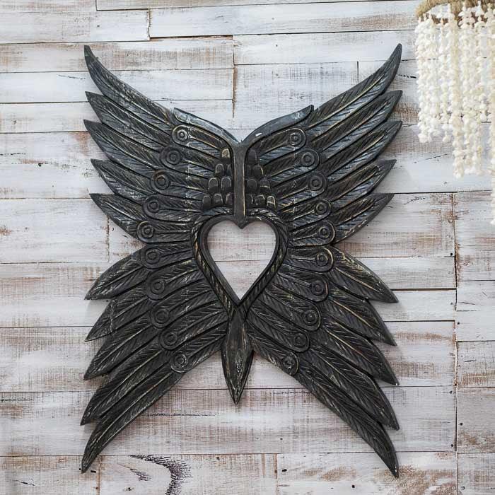 Arte tribal em madeira entalhada de Bornéu, escultura de asas com acabamento natural e formas que evocam movimento, leveza e harmonia espiritual. 