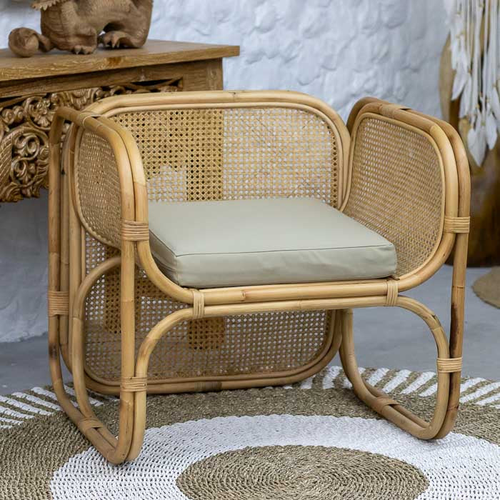 Poltrona artesanal em rattan, com design curvado e almofada de assento clara.