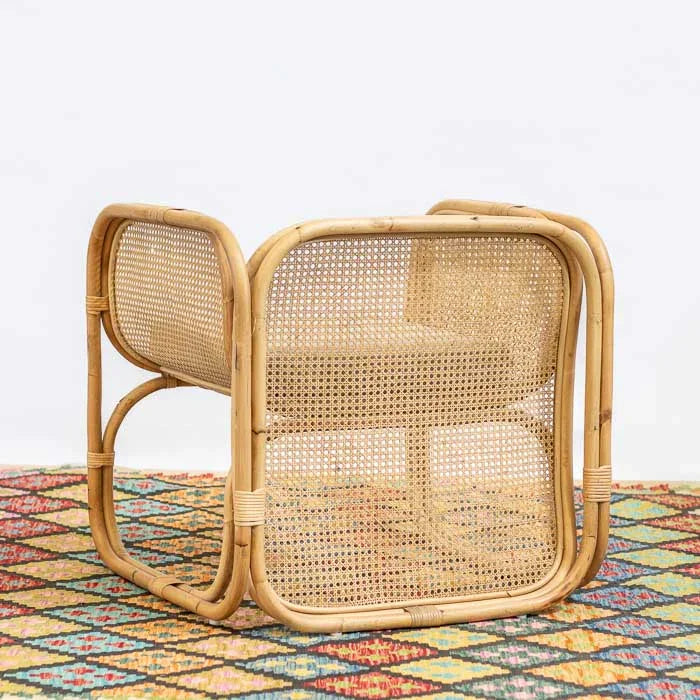 Poltrona artesanal em rattan, com design curvado e almofada de assento clara.