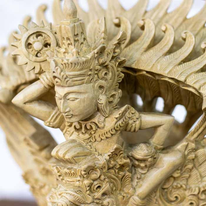 Escultura decorativa balinesa do Deus Vishnu sobre a ave mítica Garuda entalhada em madeira clara com asas abertas. 