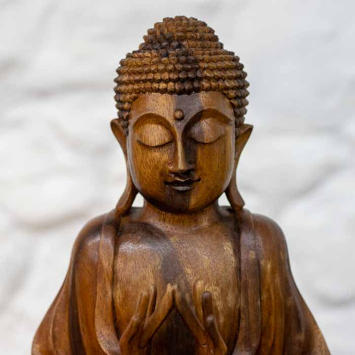 Estatueta decorativa balinesa de Buda em repouso meditativo esculpida em madeira nobre de tom mel aquecido. 