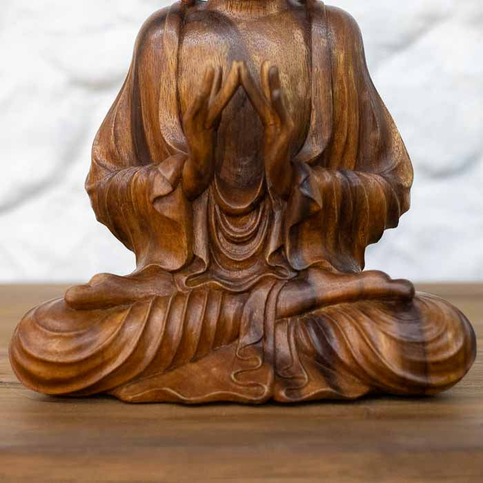 Peça de arte oriental e espiritual de Buda com expressão serena e mãos em mudra sagrado. 