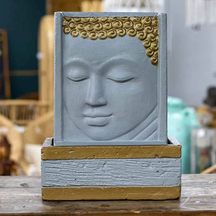 Fonte tipo paredão com face de Buda esculpida em Bali, água descendo pelo rosto. 