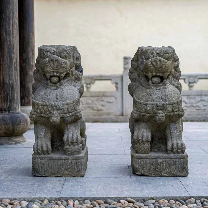 Par de esculturas imperiais Leões Fu em pedra vulcânica cinza esculpidas à mão em Bali.