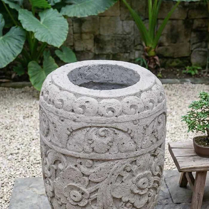 Vaso de grandes dimensões para paisagismo em ambiente externo com fundo de folhagens verdes.