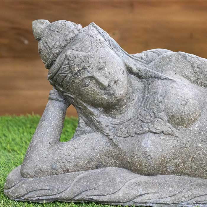 Figura feminina reclinada em pedra representando Dewi, deusa ligada à beleza e espiritualidade na cultura indonésia