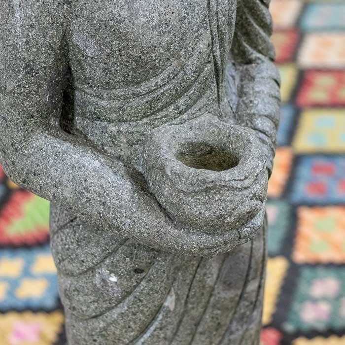 Escultura artesanal de Buda em pedra, com detalhes finos no rosto e nas vestes. 