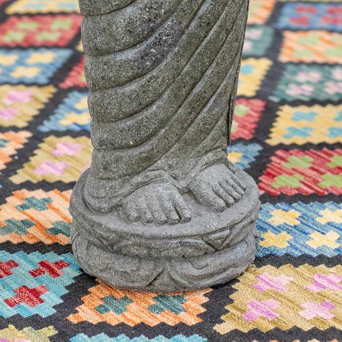 Escultura artesanal de Buda em pedra, com detalhes finos no rosto e nas vestes. 