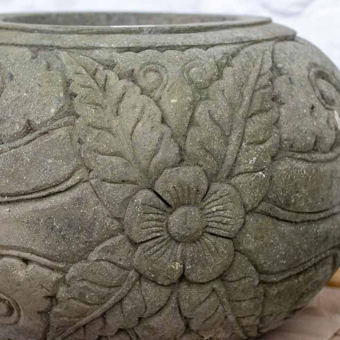 Detalhe da textura porosa e dos desenhos botânicos em vaso de pedra natural de Bali.