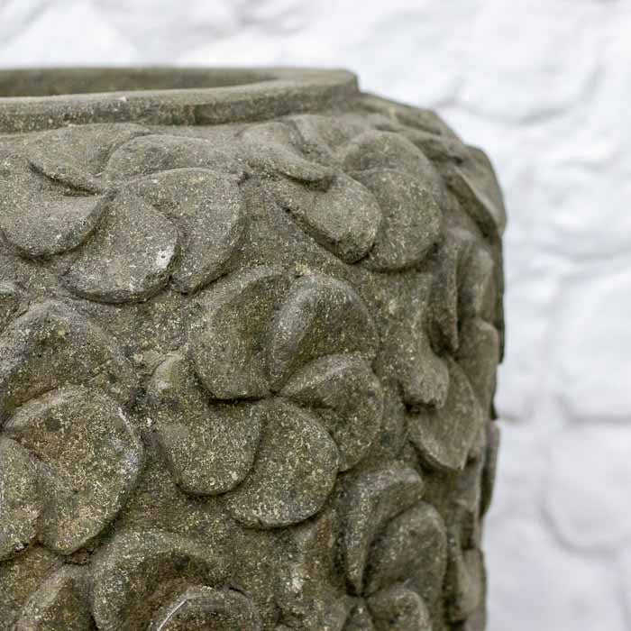 Detalhe do trabalho manual indonésio em vaso de pedra com padrão floral repetitivo.