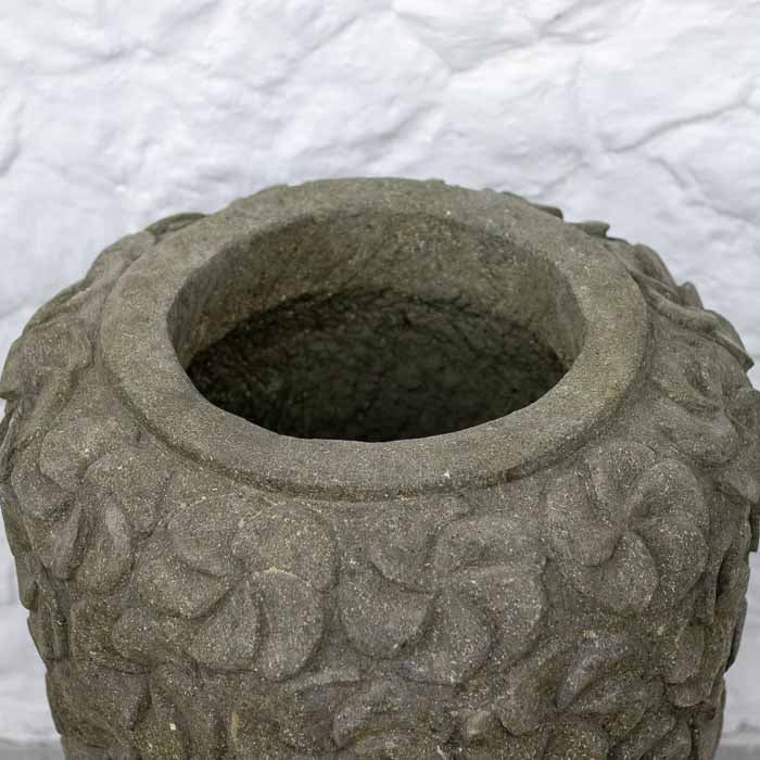 Vaso de paisagismo de luxo em pedra vulcânica posicionado contra parede de pedra branca.