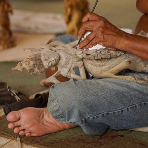 Artesão balinês esculpindo deusa hindu em madeira maciça.