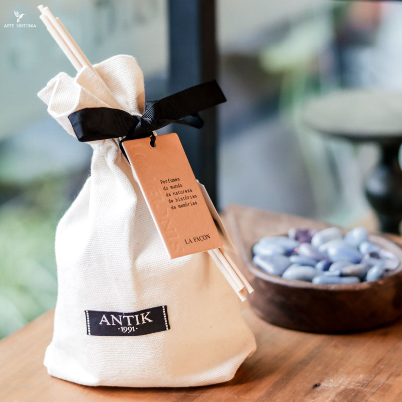 Difusor de ambiente Mangue Vert posicionado sobre superfície de madeira rústica, destacando a elegância do design. 