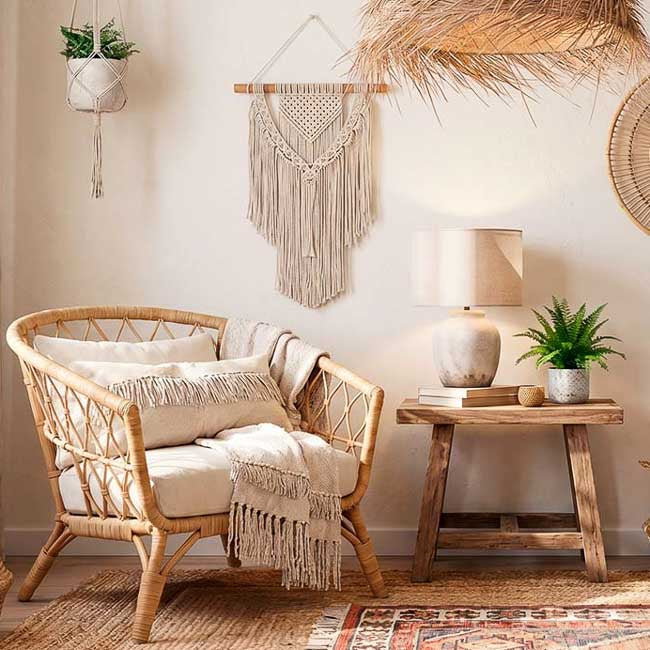 Espaço com decoração jampandi convidativo para relaxar em cadeira de rattan e itens em algodão cru.