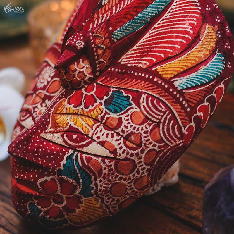 Máscara artesanal com pintura Batik em tons variados, ideal para compor coleções de arte étnica e paredes de galerias.
